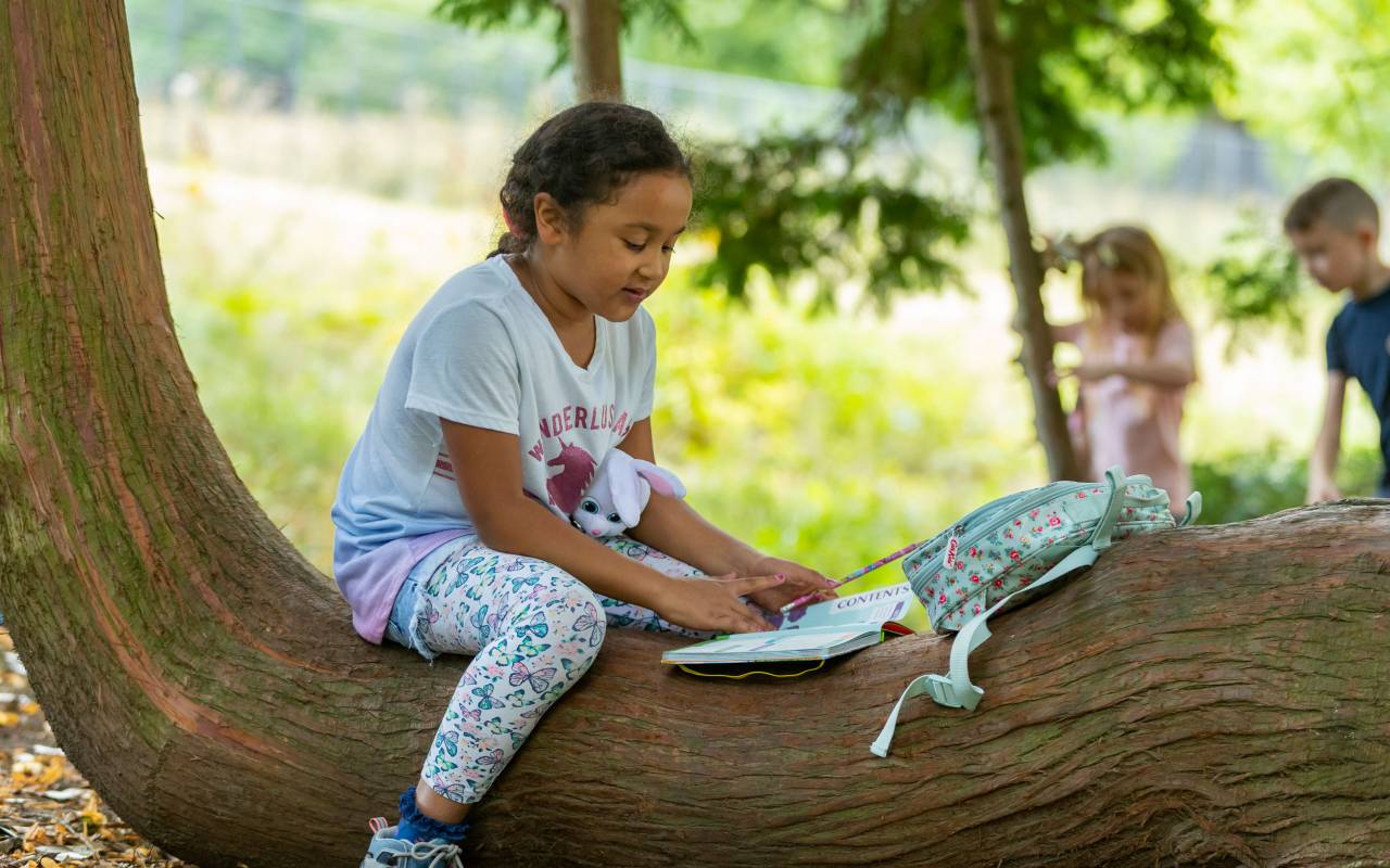 Girl sat on a tree trunk doing an activity