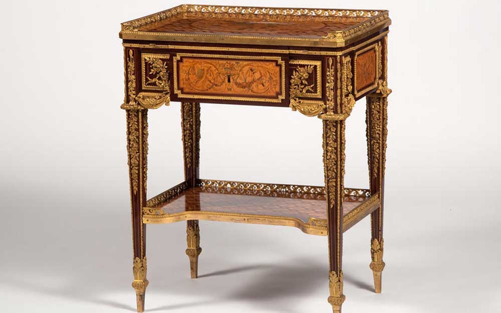 Small writing table veneered with fret marquetry and five panels depicting trophies of the arts, with elaborate gilt-bronze mounts.