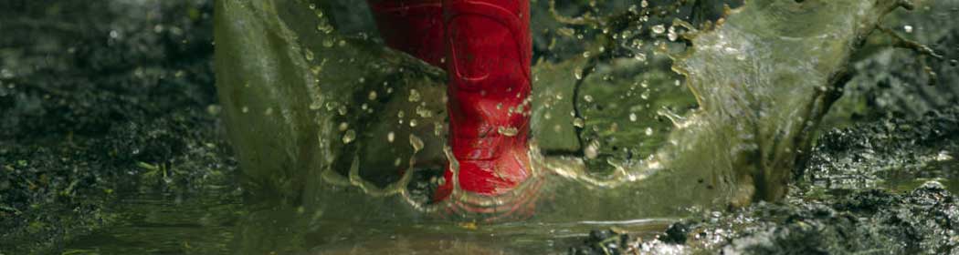 Red wellington boots splashing in a puddle